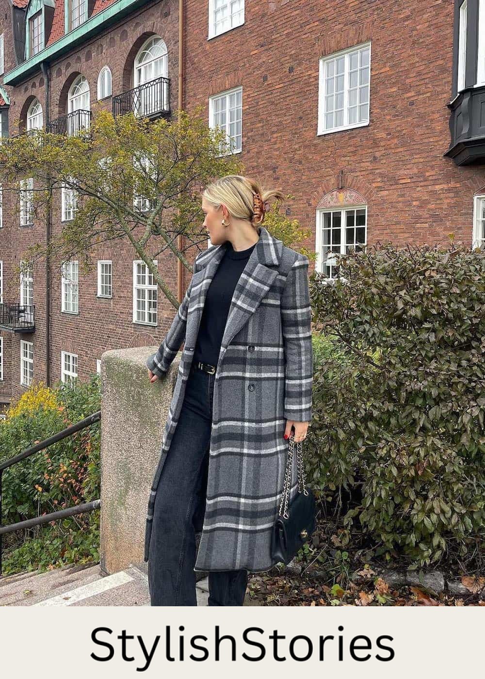 Woman wearing black jeans with a black knit top and a grey, white and black wool coat.