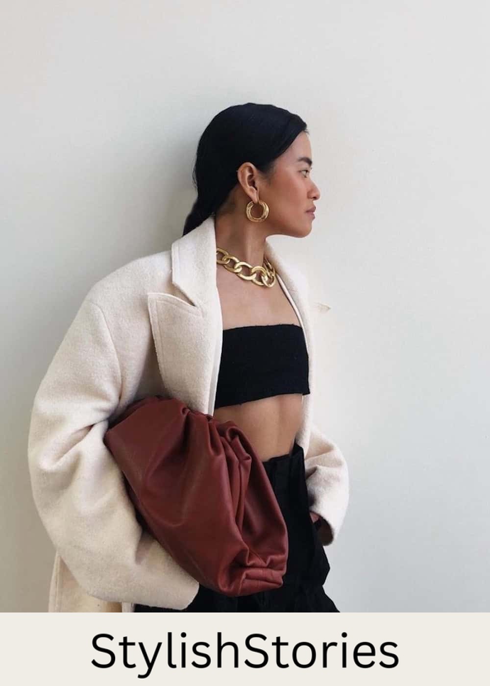 Woman wearing black trousers with a black cropped tube top and a white coat.
