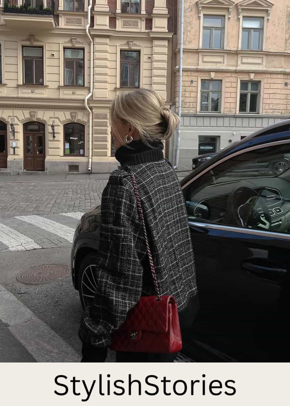 Woman wearing a plaid jacket with a a black turtle neck sweater and a red Channel bag.