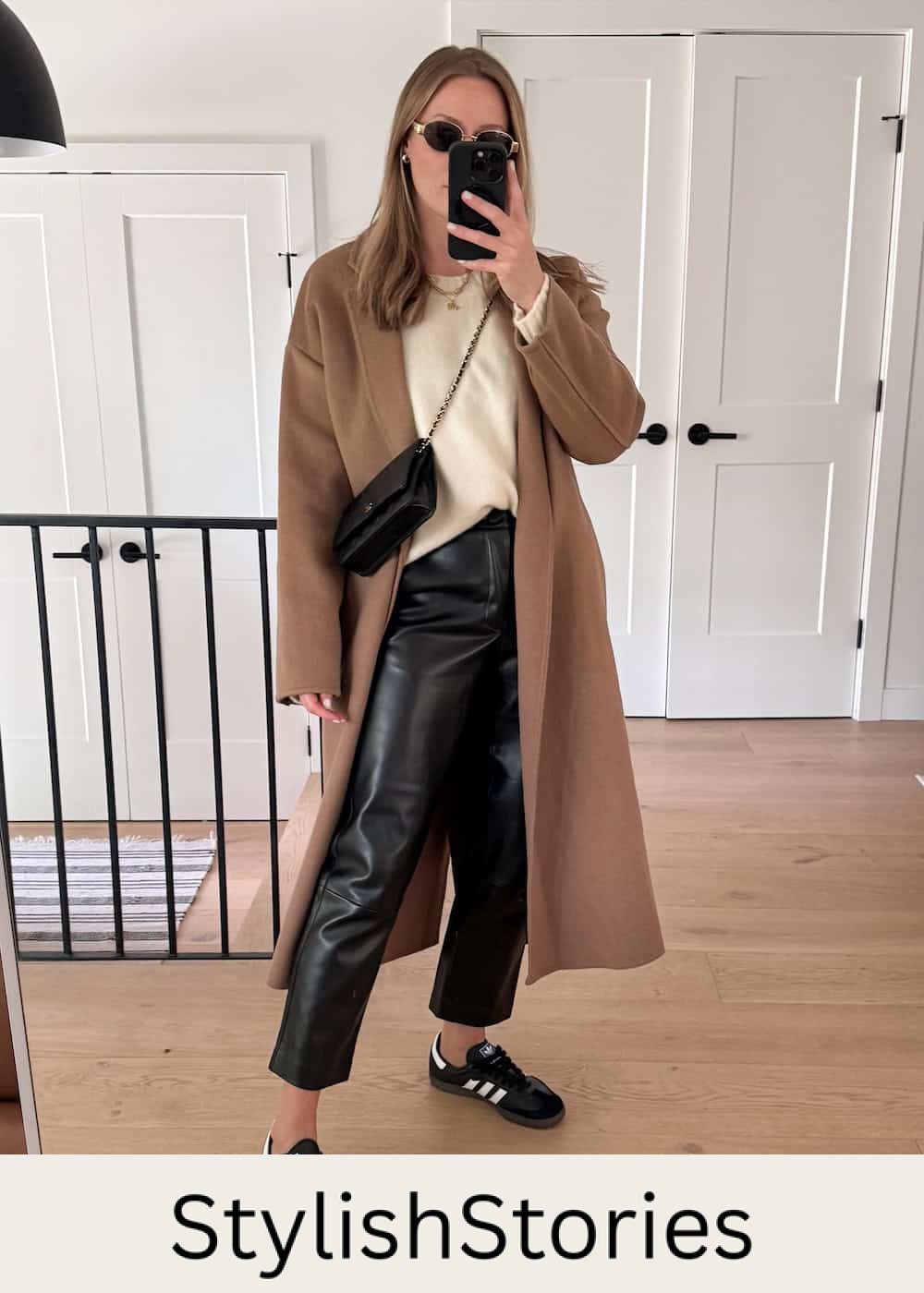 Christal wearing leather pants with sneakers and a white sweater under a long brown coat.