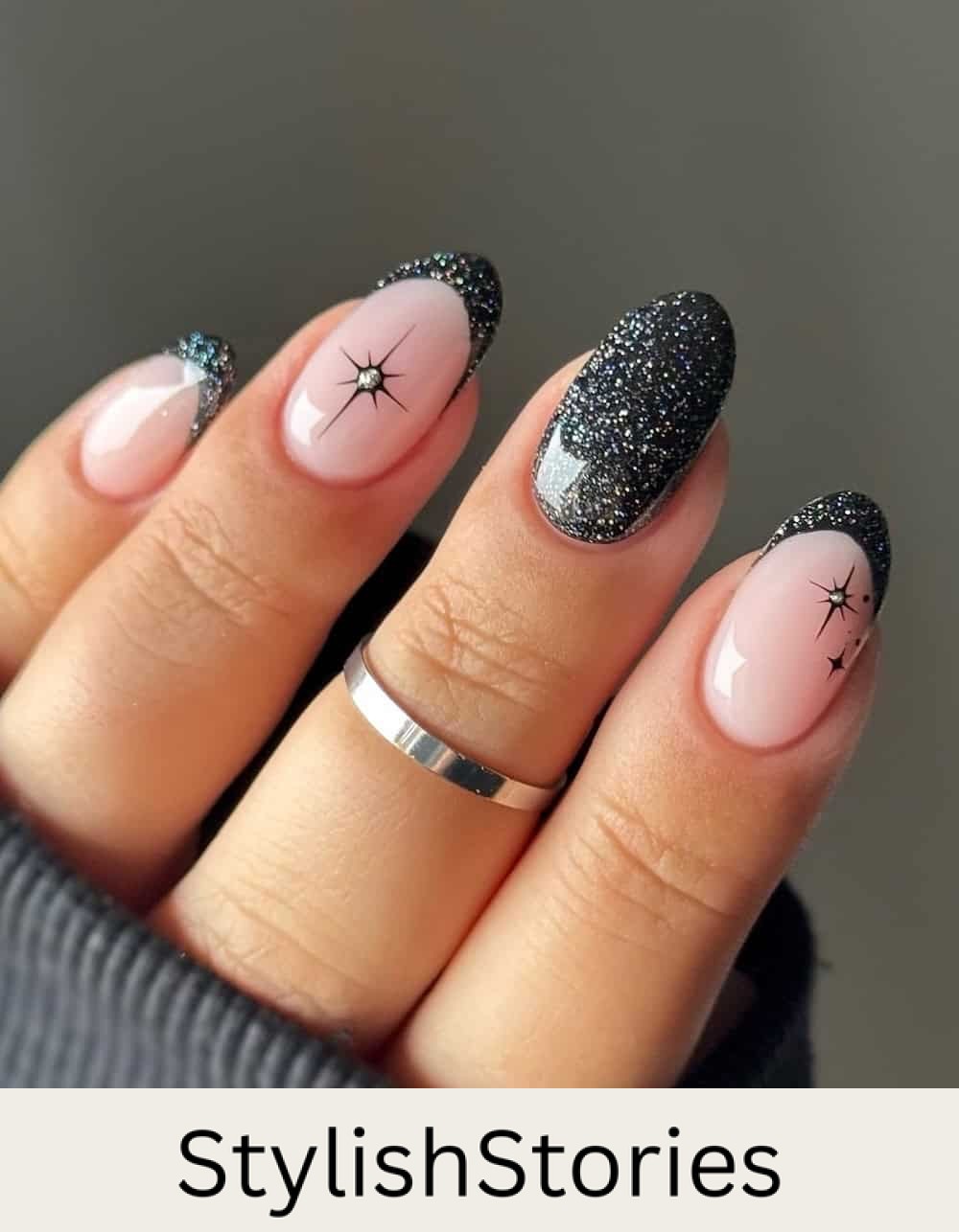 short nude nails with black glitter polish and sparkle accents